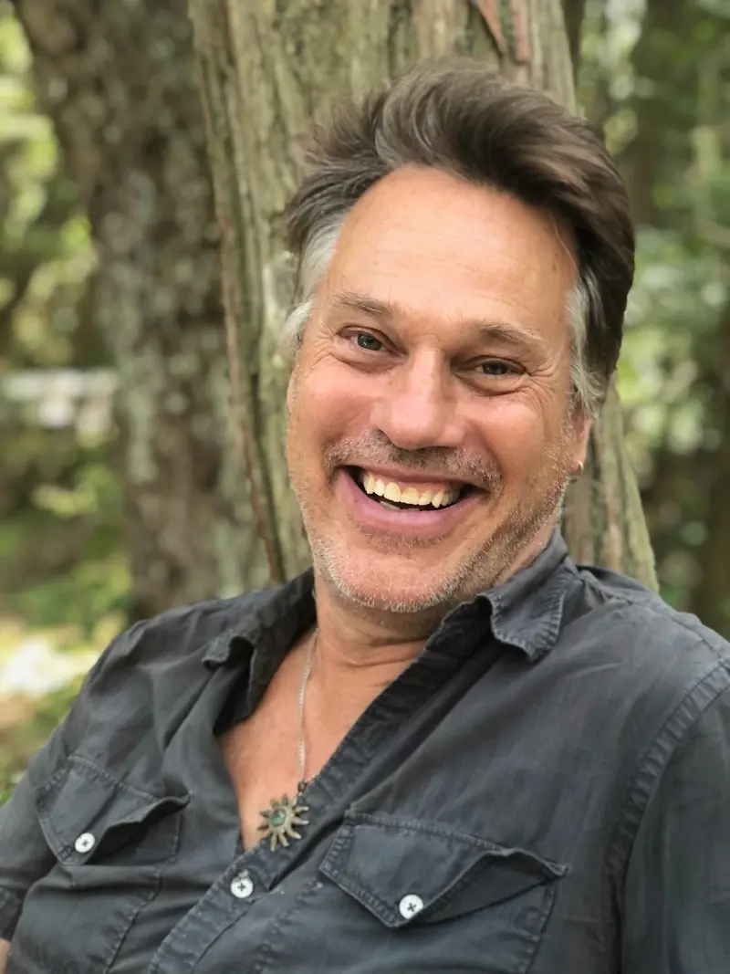 A man with long hair and smiling at the camera.