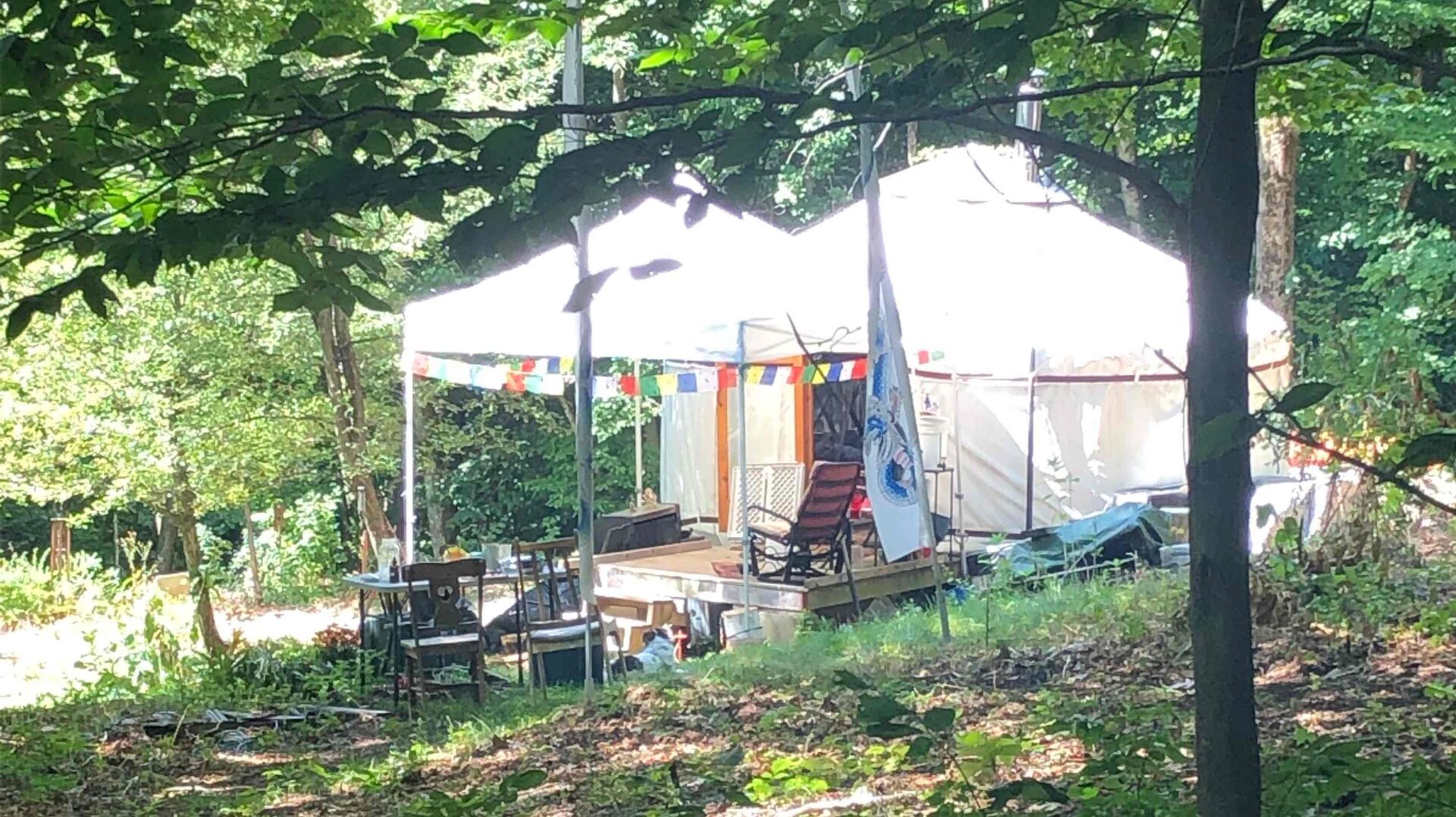 A tent with many chairs and tables in the woods.